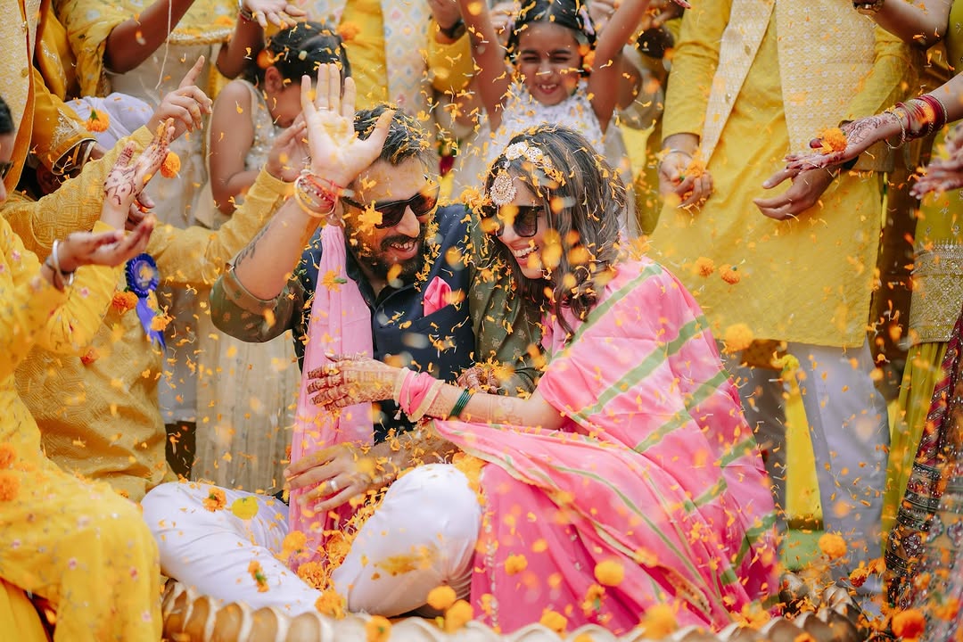 Couple covered in yellow petals during haldi